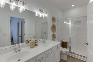 A bathroom with a large mirror, two sinks, a toilet, and a glass-enclosed shower. - Tranquil 3-bedroom townhome with AC in vibrant Atlanta (Atlanta)