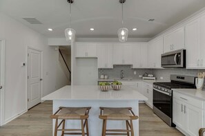 A modern kitchen with white cabinetry, a large island with stools, stainless steel appliances, and pendant lighting. - Tranquil 3-bedroom townhome with AC in vibrant Atlanta (Atlanta)