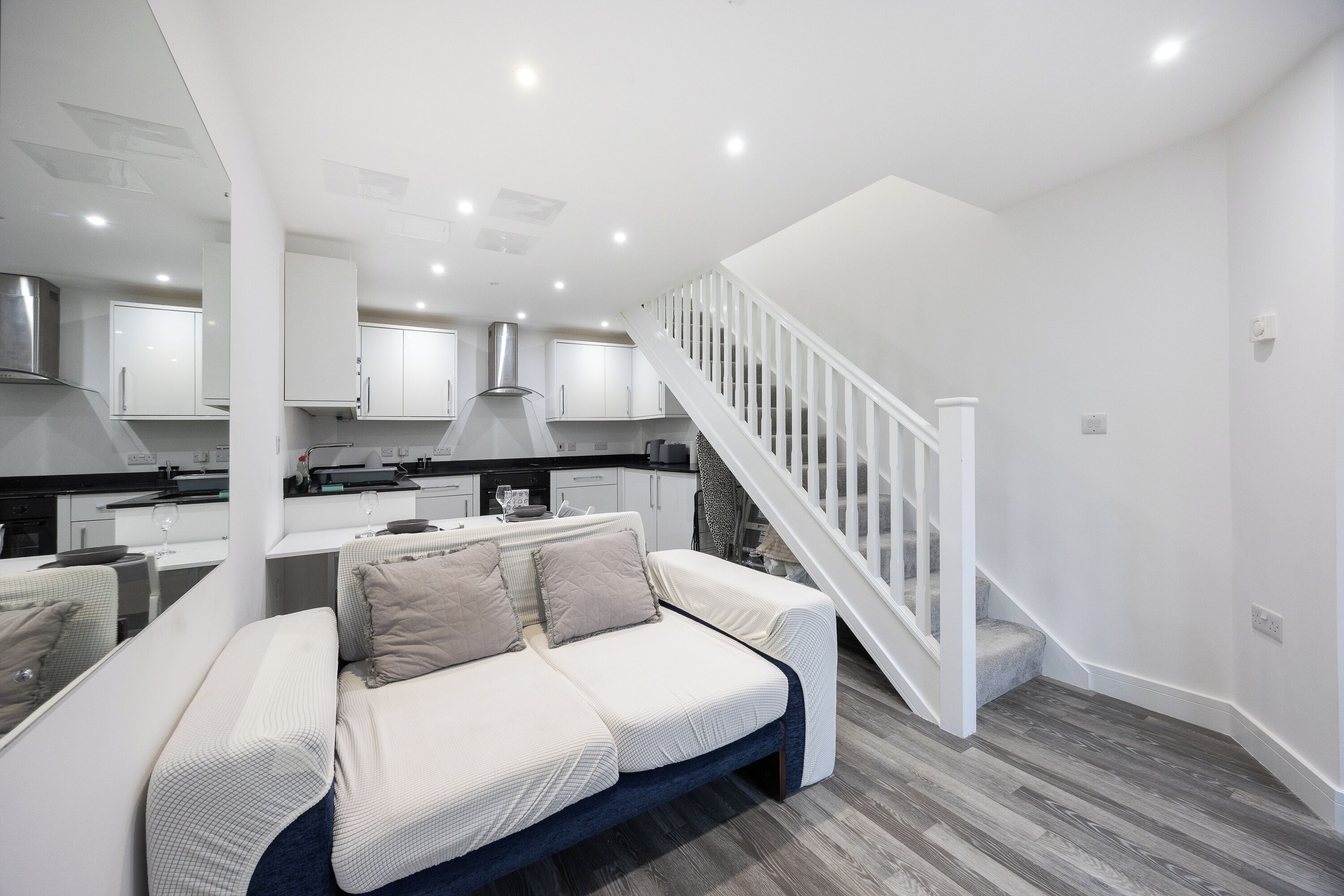 A modern kitchen with white cabinets, a central island, and a staircase leading to an upper level.