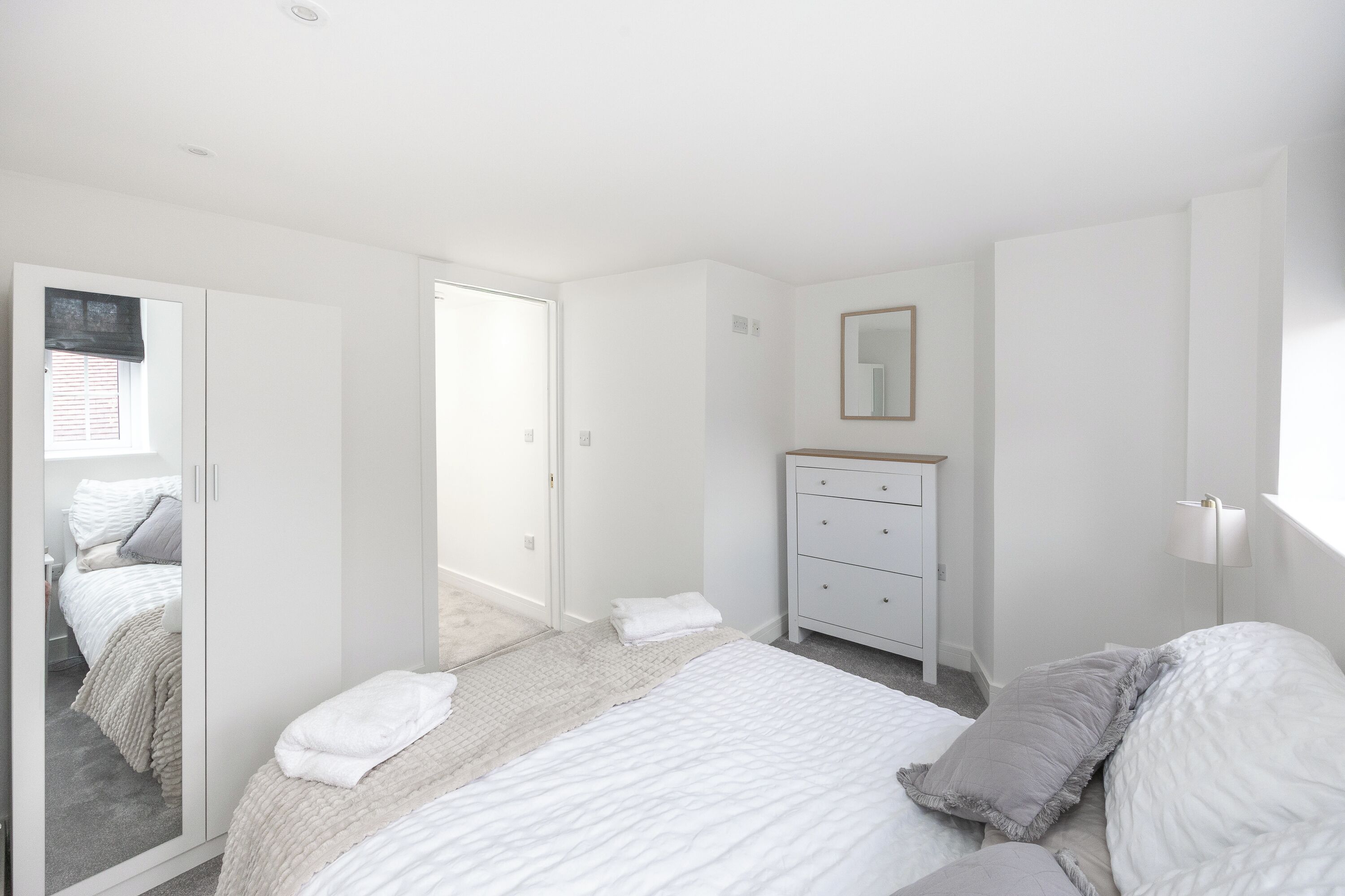 Une chambre à coucher avec un lit, une commode et un miroir.