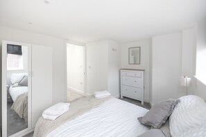 Une chambre à coucher avec un lit, une commode et un miroir.