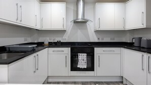 A modern kitchen with white cabinets, a black countertop, and stainless steel appliances.