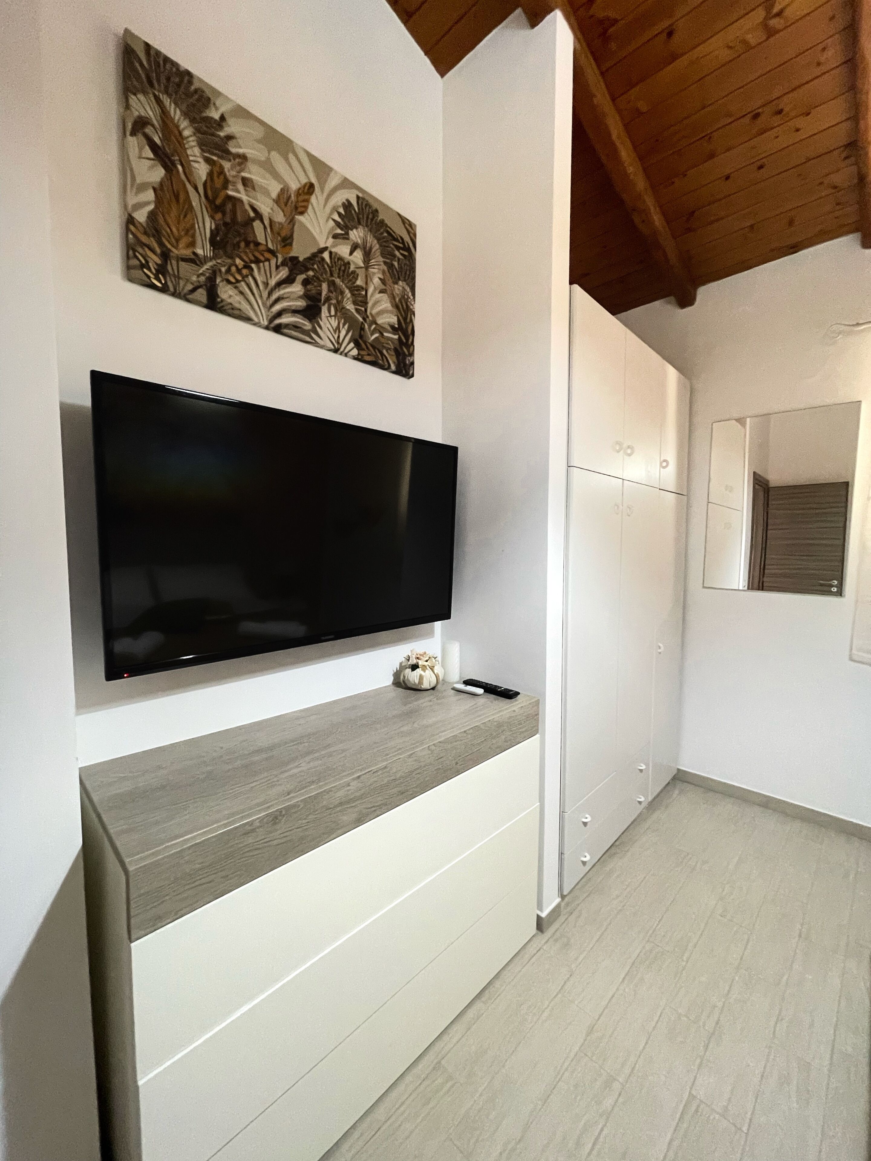 Una cucina moderna con una TV a schermo piatto montata a parete, un piano di lavoro in legno e un forno integrato.