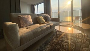Ein modernes Wohnzimmer mit einer Couch, einem runden Couchtisch und Meerblick durch große Fenster.