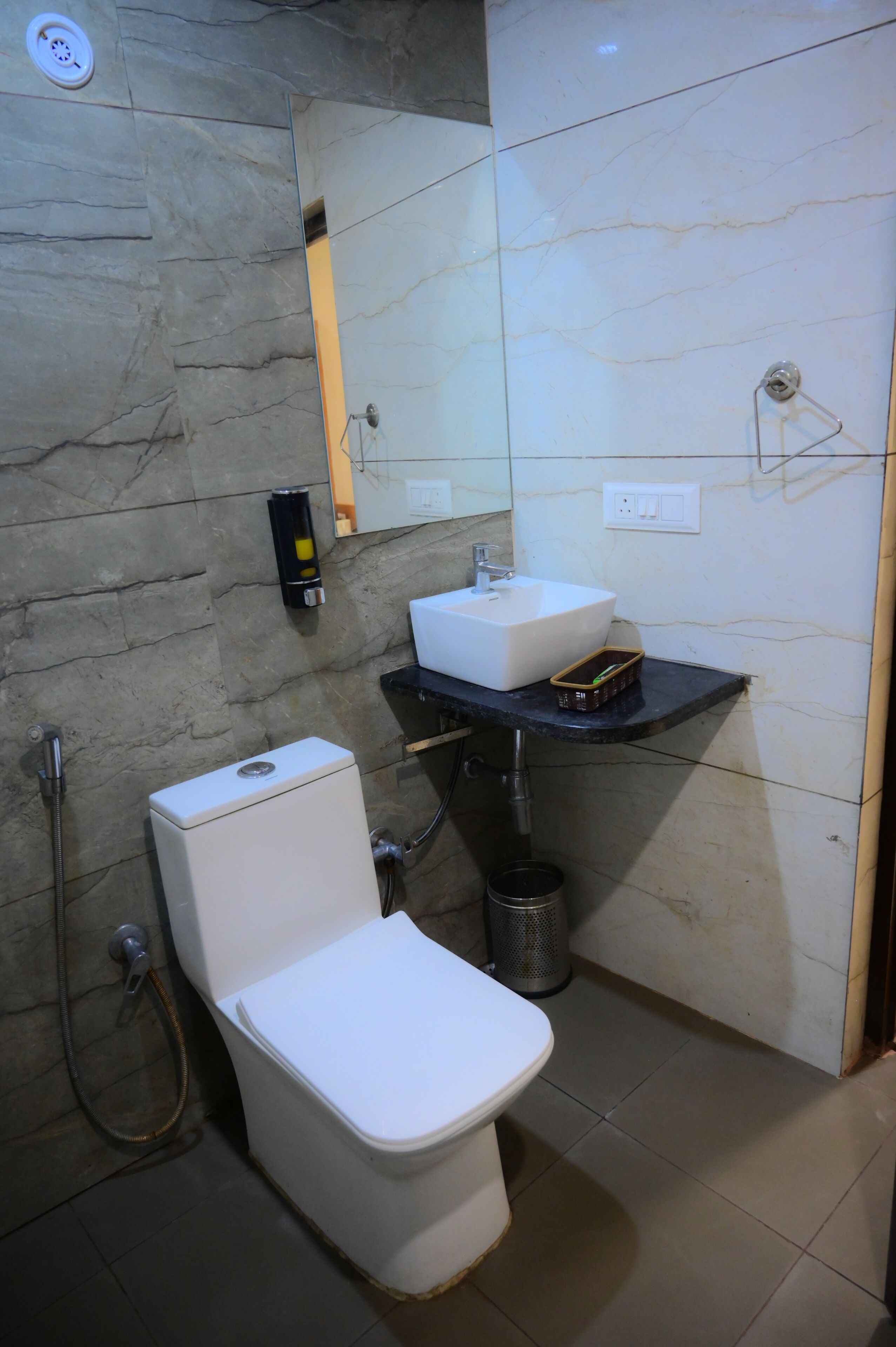 Un baño con inodoro, lavamanos, espejo y ducha.