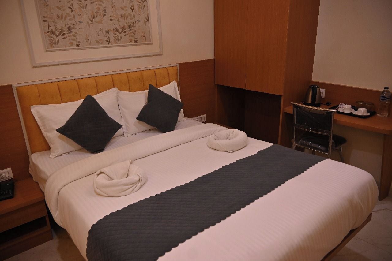 Una cama bien hecha con almohadas, una mesita de noche con una tetera y una botella de agua en la mesita de noche.