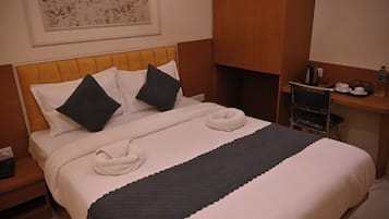 Una cama bien hecha con almohadas, una mesita de noche con una tetera y una botella de agua en la mesita de noche.