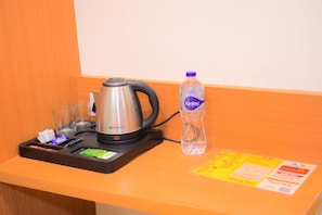 Una kitchenette con una tetera, una botella de agua y un menú sobre una mesa de madera.