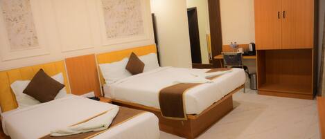 A hotel room with two beds, a wardrobe, a desk with a chair, and a mirror.
