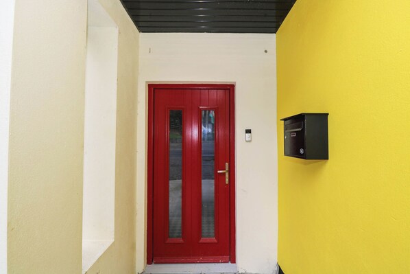 A red door with a mail slot, a yellow wall, and a black mailbox. - THE COTTAGE, pet friendly, with open fire in Leenane, County Galway (Lenane)