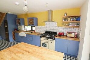 A compact kitchen with blue cabinets, a wooden countertop, a stove, and a red toaster. - THE COTTAGE, pet friendly, with open fire in Leenane, County Galway (Lenane)