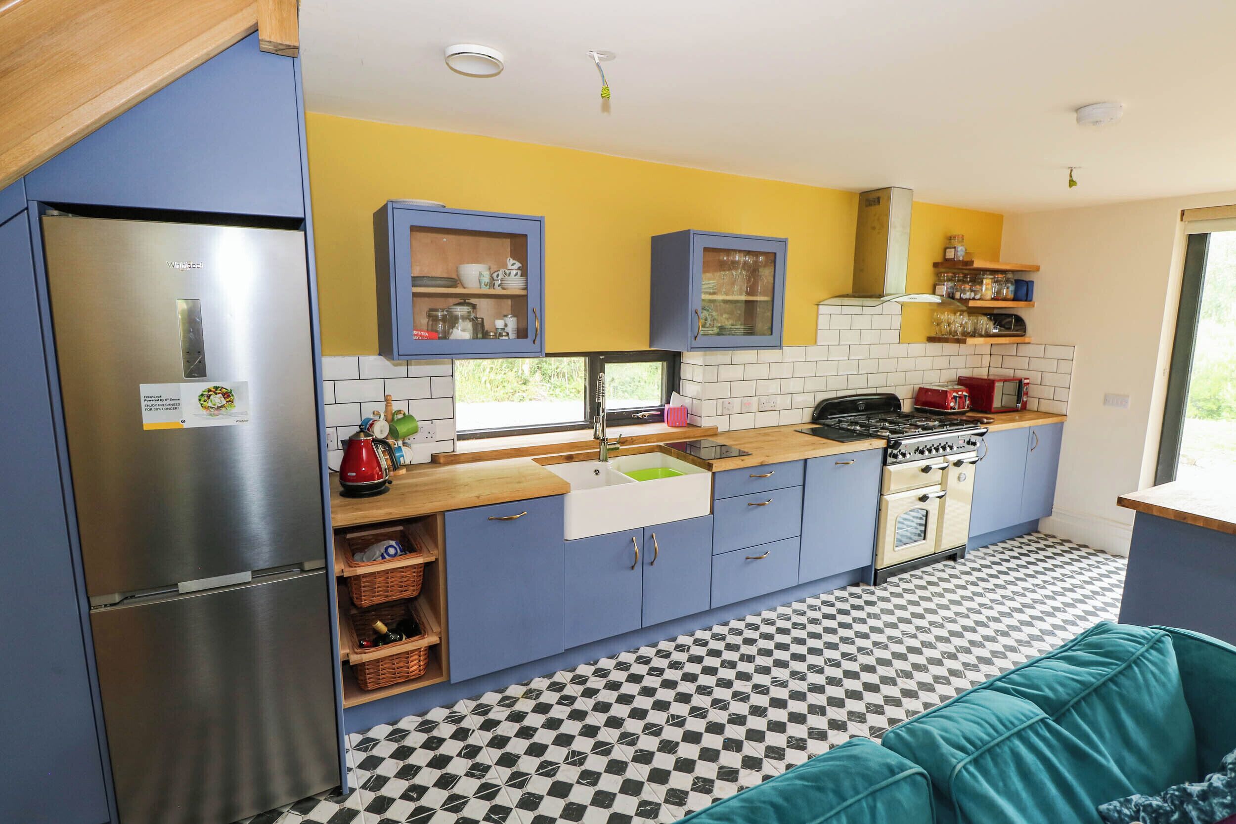 Cocina compacta con refrigerador, estufa, lavaplatos y gabinetes azules.