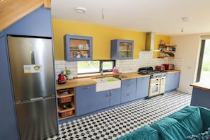 A compact kitchen with a refrigerator, stove, sink, and blue cabinets.