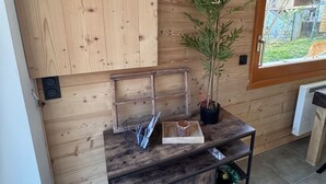 Quarto com painel de parede de madeira, um relógio, uma planta em vaso e uma pequena mesa com bandeja.