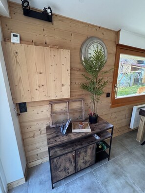 Ein Zimmer mit Holzvertäfelung, einer Uhr, einem Blumentopf und einem kleinen Tisch mit Tablett.