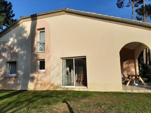 En toetages bygning med beige facade, store vinduer og en rundbuet indgang.
