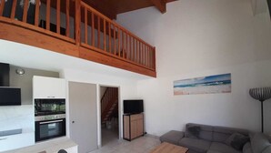 A modern living space with a kitchen, dining area, and a seating area with a sofa and coffee table. - Residence with a pool next to the Moliets Golf Course; Duplex apartment for 8–9 people, 10 minutes from the ocean (Moliets-et-Maa)