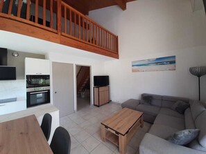 A modern living space with a kitchen, dining area, and a seating area with a sofa and coffee table. - Residence with a pool next to the Moliets Golf Course; Duplex apartment for 8–9 people, 10 minutes from the ocean (Moliets-et-Maa)