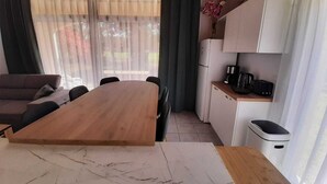 A modern kitchen with a wooden dining table, a built-in oven, and a coffee maker. - Residence with a pool next to the Moliets Golf Course; Duplex apartment for 8–9 people, 10 minutes from the ocean (Moliets-et-Maa)