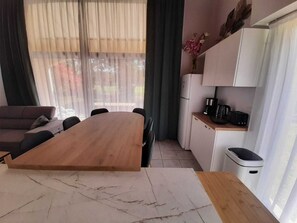 A modern kitchen with a wooden dining table, a built-in oven, and a coffee maker. - Residence with a pool next to the Moliets golf course; duplex apartment for 8–9 people, 10 minutes from the ocean (Moliets-et-Maa)