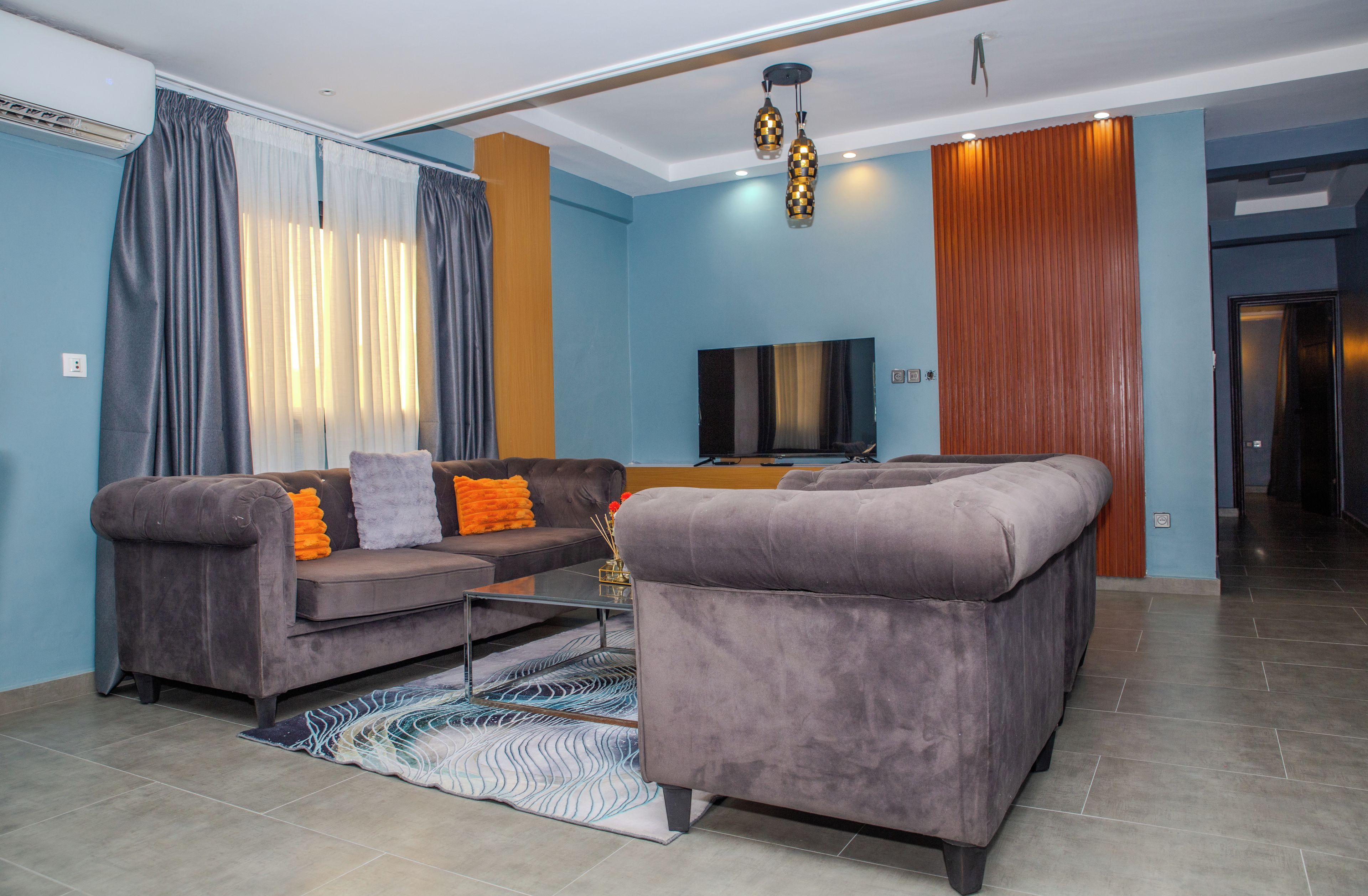 A modern living room with a sectional sofa, a flat-screen TV, and a decorative rug.