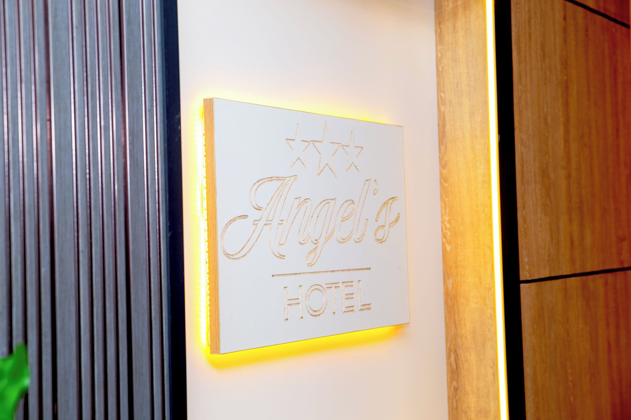 A sign with the name 'Angel's Hotel' illuminated by a light strip.