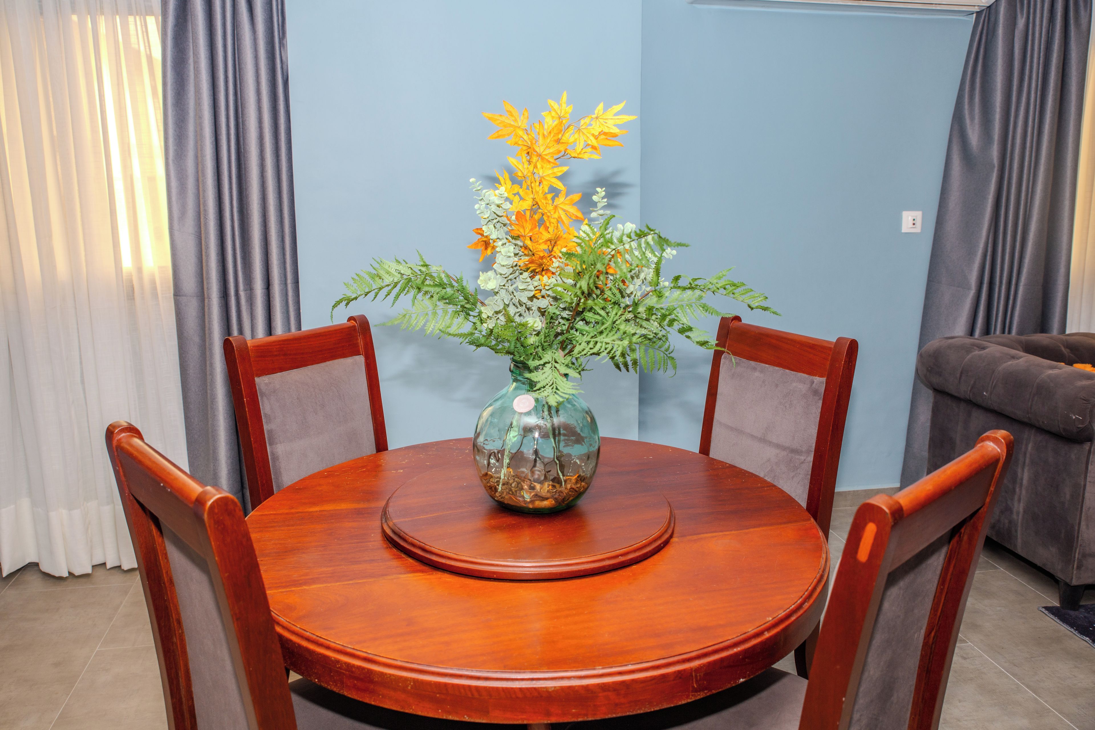 Mesa de jantar com um vaso de flores, rodeada por cadeiras.