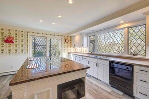A modern kitchen with a central island, white cabinetry, and a dishwasher. - 1 Mi to Beach: Spacious 5-bedroom house in terrific Sandwich with AC (Sandwich)