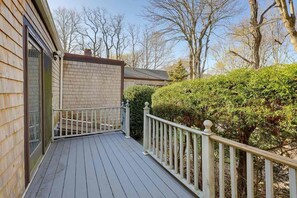 A wooden deck with a white railing, a brick wall, and a well-maintained hedge. - 1 Mi to Beach: Spacious 5-bedroom house in terrific Sandwich with AC (Sandwich)