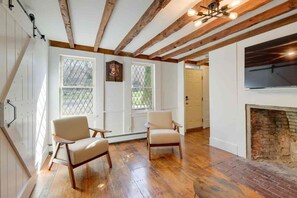 A room with wooden beams, a fireplace, two chairs, and a TV. - 1 Mi to Beach: Spacious 5-bedroom house in terrific Sandwich with AC (Sandwich)