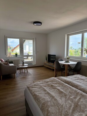 Ein Schlafzimmer mit zwei Betten, einem Fernseher, einem Esstisch mit Stühlen und einem Sofa.