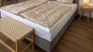A double bed with floral bedding, a bedside table, a lamp, and a wooden shelf unit. - Apartment with a large terrace and a view of the Black Forest (Willstätt)