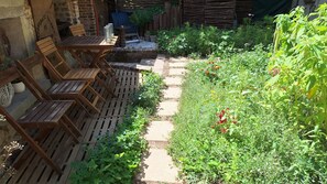 A garden with a wooden deck, chairs, and a table. - Charming French cottage/charming country house (Le Plessis-Dorin)