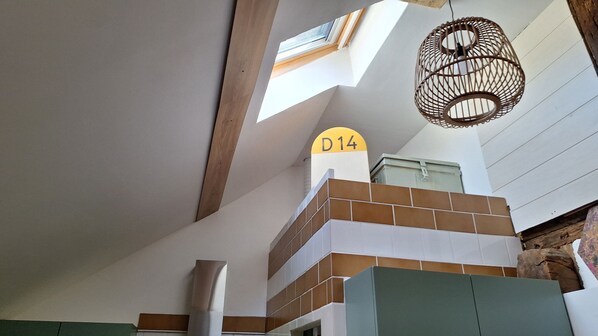A room with a high ceiling, a skylight, a sign with the number 'D14', and a hanging light fixture. - Charming French cottage/charming country house (Le Plessis-Dorin)