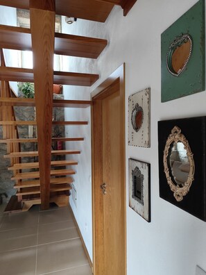 Eine Treppe mit Holzwertlauf, die zu einer Tür führt, eine Wand mit dekorativen Spiegeln und ein Fliesenboden.