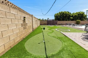 Um campo de minigolfe com um muro de tijolos de um lado e uma cerca de madeira do outro.
