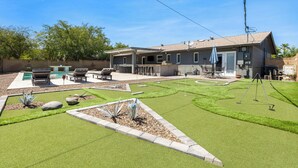 Um imóvel residencial com piscina, móveis de pátio e um gramado bem cuidado.