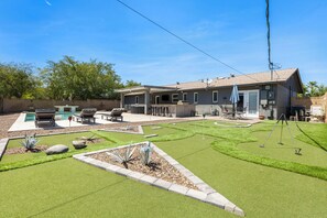 Ein Wohnhaus mit Swimmingpool, Terrassenmöbeln und einem gepflegten Rasen.