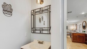 Um banheiro com pia, espelho e arte de parede decorativa com cactos.