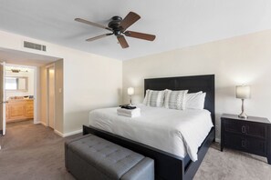 A hotel room with a bed, a bedside table, a bench, a ceiling fan, and a bathroom visible through an open door. - Scottsdale Old Town Basecamp | Single-Level 3BR, Pool Access & Golf 🌵⛳ (Scottsdale)