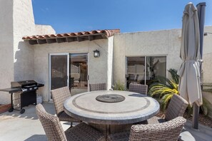 A patio with a round table and wicker chairs, a grill, and a covered umbrella. - Scottsdale Old Town Basecamp | Single-Level 3BR, Pool Access & Golf 🌵⛳ (Scottsdale)