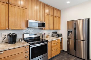 A modern kitchen with wooden cabinets, stainless steel appliances, and a tiled backsplash. - Scottsdale Old Town Basecamp | Single-Level 3BR, Pool Access & Golf 🌵⛳ (Scottsdale)