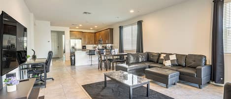 A modern living room with a sectional sofa, a coffee table, and a dining area with chairs.