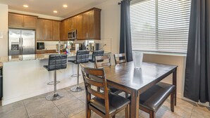 A modern kitchen with wooden cabinets, stainless steel appliances, and a dining area with a table and chairs. - Wfh-friendly Phoenix Home w/ Easy Freeway Access (Phoenix)