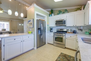 A modern kitchen with white cabinetry, stainless steel appliances, and pendant lighting. - Freshly Updated, Flip-flop 2 Blocks to Beach! (New Smyrna Beach)