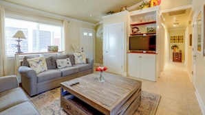 A living room with a sofa, coffee table, and a television. - Flip-flop to Beach & Flagler Ave! Breezy Getaway (New Smyrna Beach)