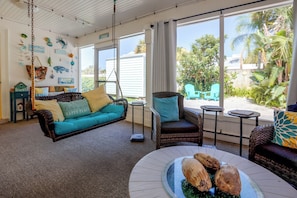 A room with a hanging chair, a sofa, and a dining table with coconuts.