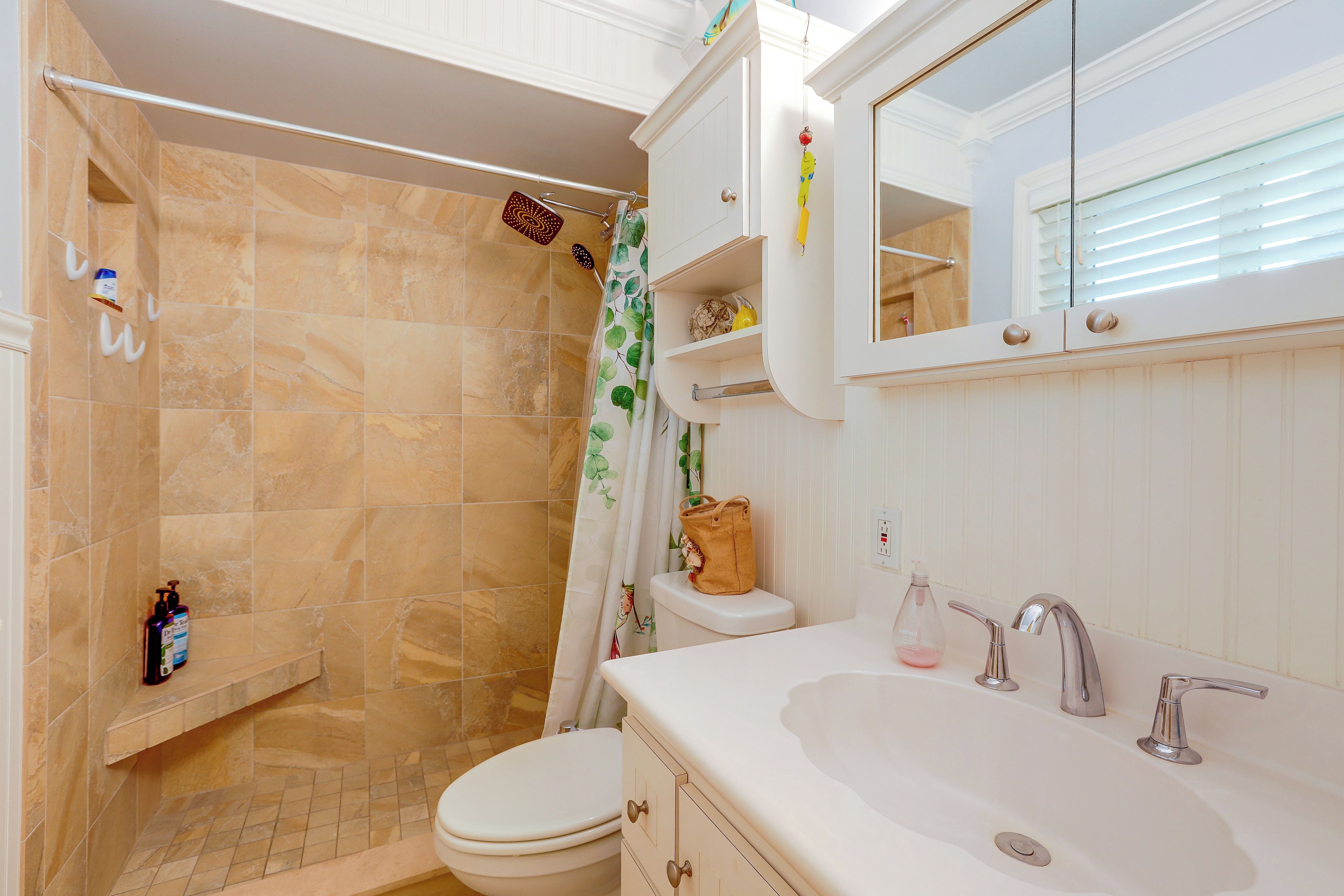 A bathroom with a shower, toilet, sink, and a mirror.