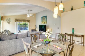 A modern living room with a glass dining table, a sofa, and a ceiling fan. - Heated Pool & Game Room! Family Hub 9 Mi to Disney (Davenport)