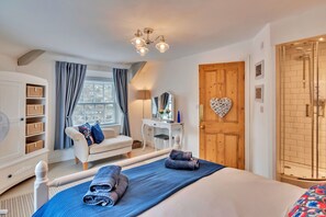 Ein Schlafzimmer mit einem Bett, einem Schreibtisch, einem Stuhl, einem Kleiderschrank und einem Fenster mit Vorhängen.